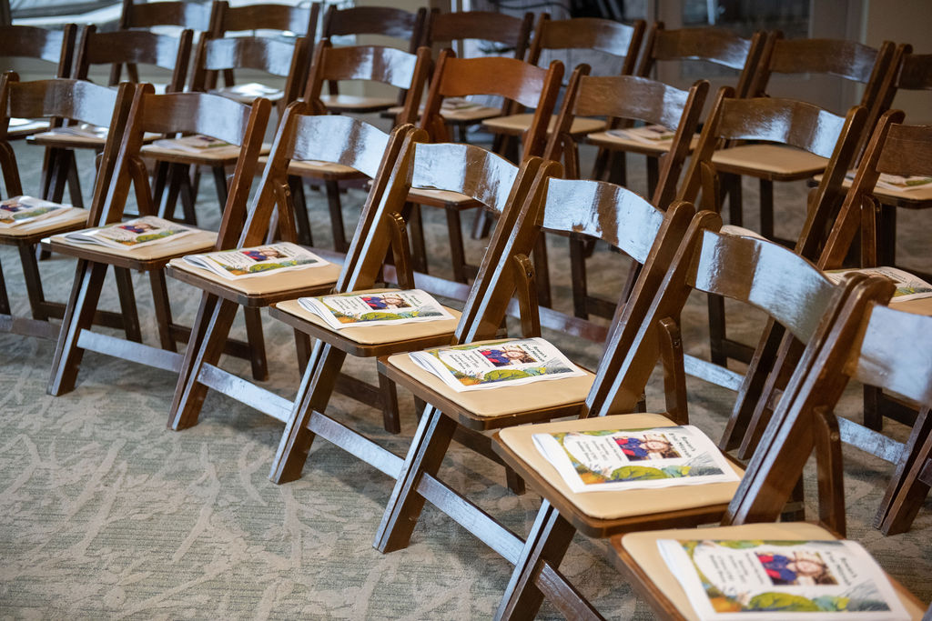 Wooden chairs with service booklet on top at Rowan's Enchanted Forest B'nai Mitzvah at Bretton Wood Country Club in Germantown, MD | Pop Color Events | Adding a Pop of Color to Bar & Bat Mitzvahs in DC, MD & VA | Photo by: Lacey Ann Photography